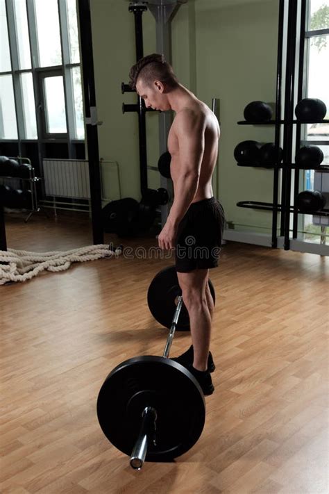 A Muscular Guy With A Naked Torso In Sports Shorts Is Running On A Kettlebell With One Hand