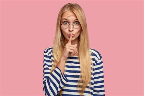 étudiante blonde secrète posant contre le mur rose Photo Gratuite