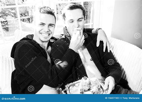 Male Gay Couple Sitting On Armchair Laughing And Feeding Each Other Cake Stock Image Image Of
