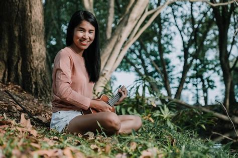 Premium Photo Portrait Of Smiling Woman Playing Ukulele While Sitting