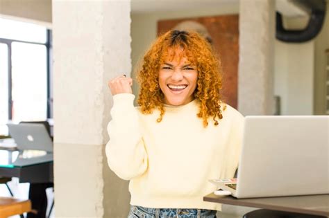 Joven pelirroja mujer bonita latina teletrabajando en casa con una computadora portátil Foto