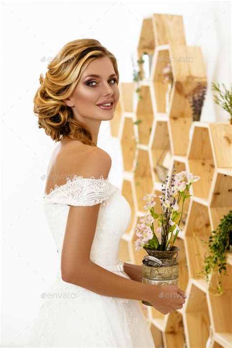 Beautiful Sexy Blonde Bride Posing In Wedding Dress In White Room