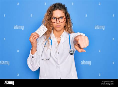 Junge Sch Ne Blonde Rztin Mit Blauen Augen Tr Gt Stethoskop Mit Pillen Zeigen Mit Finger Auf