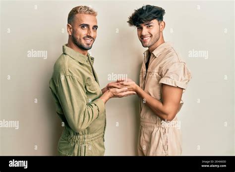 Homosexual Gay Couple Standing Together Wearing Casual Jumpsuit Pointing Aside With Hands Open