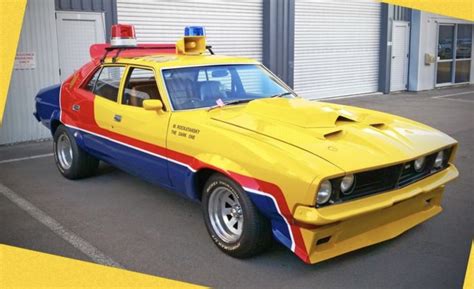 A Yellow Police Car Parked In Front Of A Building With A Red White And