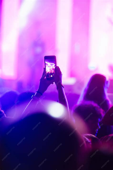 Premium Photo | Hand with a phone records live music festival People