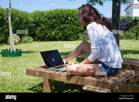 Brunette Woman With White Shirt And Jeans Shorts Using Laptop Sitting