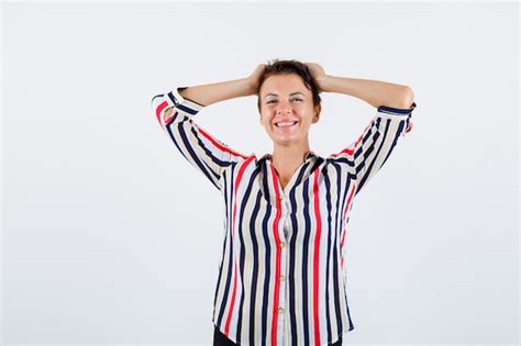 Femme mature tenant les mains sur la tête en chemisier rayé et à la flottabilité vue de face