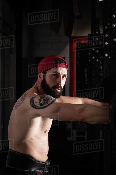Side View Of Strong Male Athlete With Naked Torso And In Weightlifting Belt Standing Near
