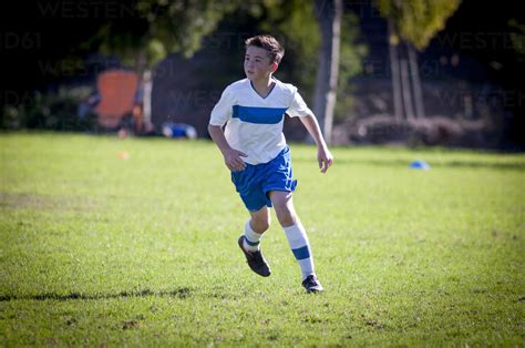 Teen soccer player running on a soccer field stock photo