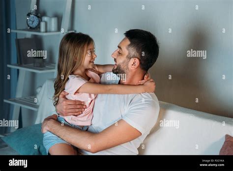 Side View Of Smiling Father And Daughter Looking At Each Other At Home