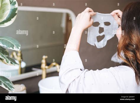 Adult Brunette Woman With Sheet Mask On Her Face In The Bathroom At Home Stock Photo Alamy