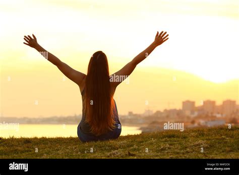 Back View Backlight Portrait Of A Single Cheerful Woman Raising Arms