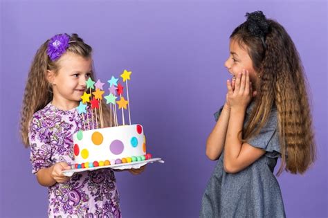 Free Photo Surprised Little Caucasian Girl Looking At Pleased Little Blonde Girl Holding