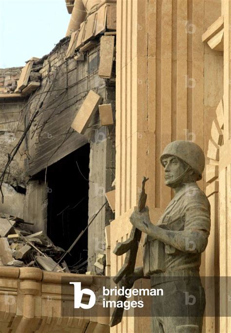 Image of A statue of an Iraqi soldier overlooks damage to Saddam