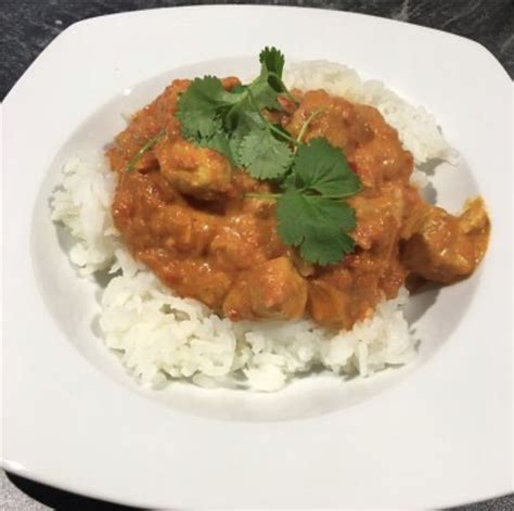 A White Plate Topped With Rice And Meat Covered In Cilantro Garnish