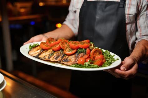 Premium Photo Chef Presenting A Plate Of Grilled Salmon Steaks To