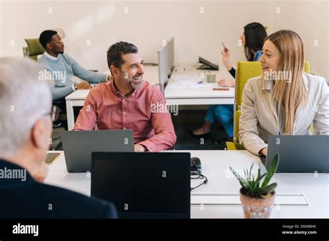 A Handsome Senior Businessman Is Listening To His Female Blonde Colleague Telling A Fun Story