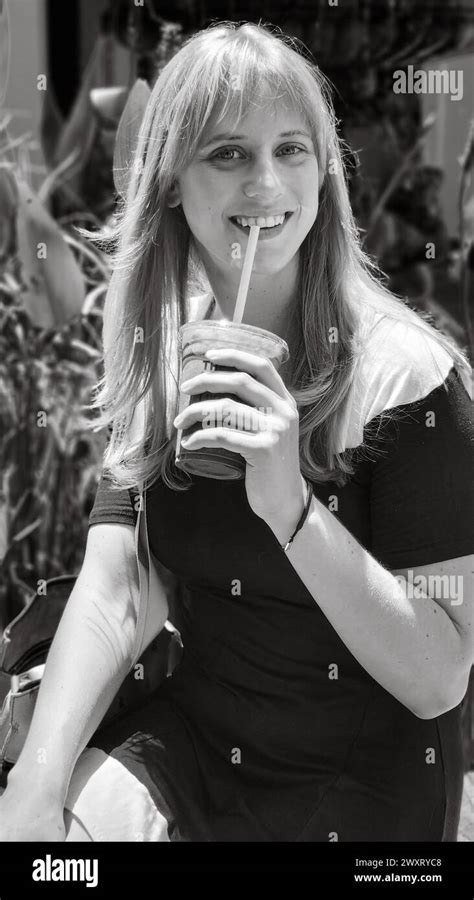 A Grayscale Of A Blonde Girl With A Drink Sitting Next To A Fountain Stock Photo Alamy