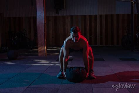 A Muscular Powerful Man With A Naked Torso Exercises With A Heavy Posters For The Wall Posters