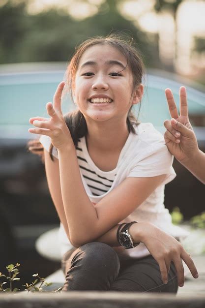 Premium Photo Portrait Of Smiling Girl Gesturing While Sitting Outdoors