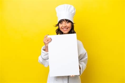 Joven chef mujer latina aislada de fondo amarillo sosteniendo un cartel vacío con expresión