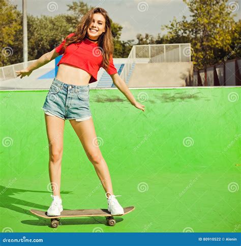 Very Beautiful Brunette Girl Posing On The Green Ramp Skate Park Standing On A Skateboard