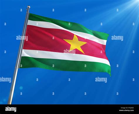 Suriname National Flag Waving On Pole Against Deep Blue Sky Background High Definition Stock