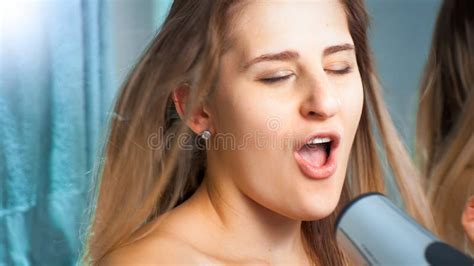 Portrait Of Beautiful Brunette Woman Singing While Drying Hair At