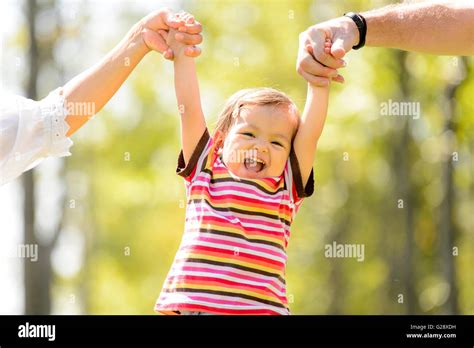 Toddler Holding Parents Hands In A Park Stock Photo Alamy