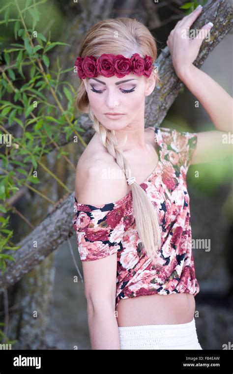 Une jeune fille blonde magnifique à bas tout en portant une couronne de fleurs rouge avec une