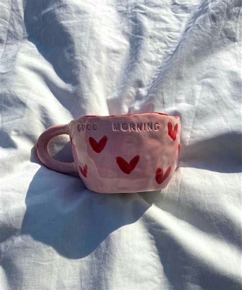 A Pink Cup With Red Hearts On It Sitting On A White Sheet That Says God