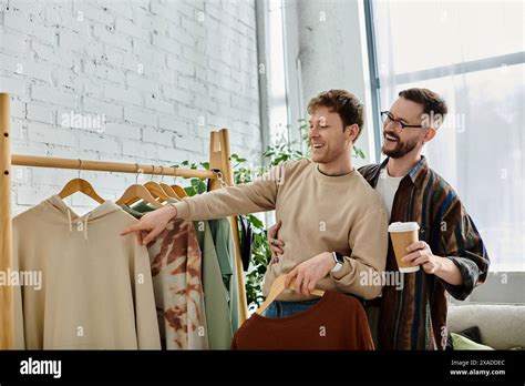 Two Men A Gay Couple Stand Together In A Designer Workshop Collaborating On Trendy Attire