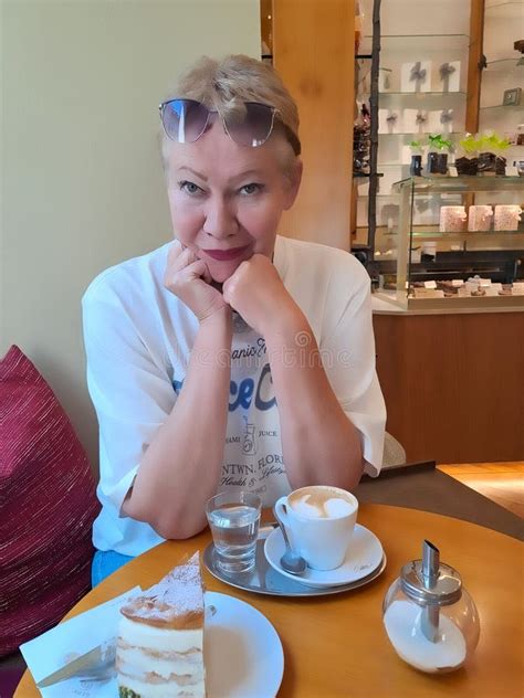 Attractive Mature Woman Sitting At The Table In Cafe With Cappuchino