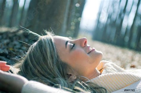 Smiling Blonde Girl Lying On Leaves In A Forest Of Stock Photo Crushpixel
