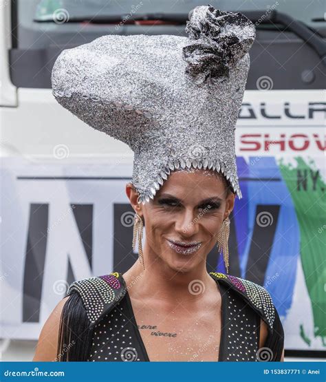 A Drag Queen Wearing An Elaborate Shoe Hat And A Black Dress Attending The Gay Pride Parade