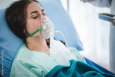 Young Woman Patient Receiving Oxygen Mask Lying On A Hospital Bed