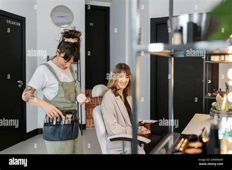Happy Make Up Artist Talking With Customer Sitting On Chair At Salon