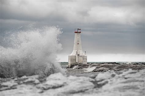 A lighthouse surrounded by waves in the ocean photo – Free Cold Image ...