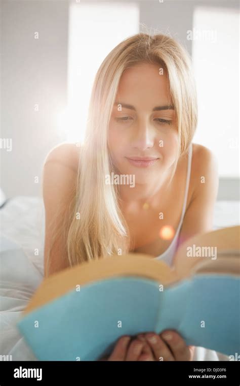 Smiling Blonde Reading A Book On Her Bed Stock Photo Alamy