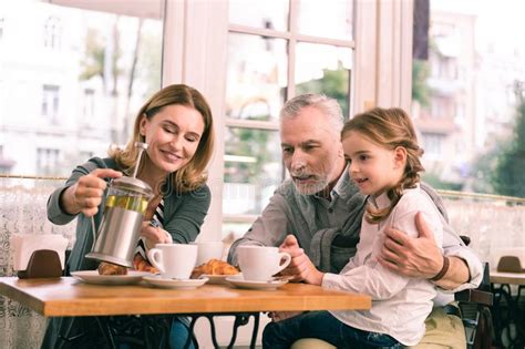 Beaming Blonde Haired Grandmother Pouring Some Tea For Her Girl Stock