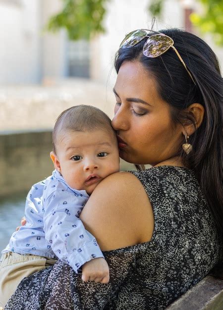 Joven Madre Latina Besando La Cabeza De Su Beb Sentada En Un Parque Foto Premium