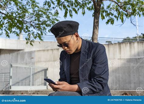 Un Joven Gay Latino Con Un Sombrero De Moda Y Gafas De Sol Mandando Mensajes De Texto En Su