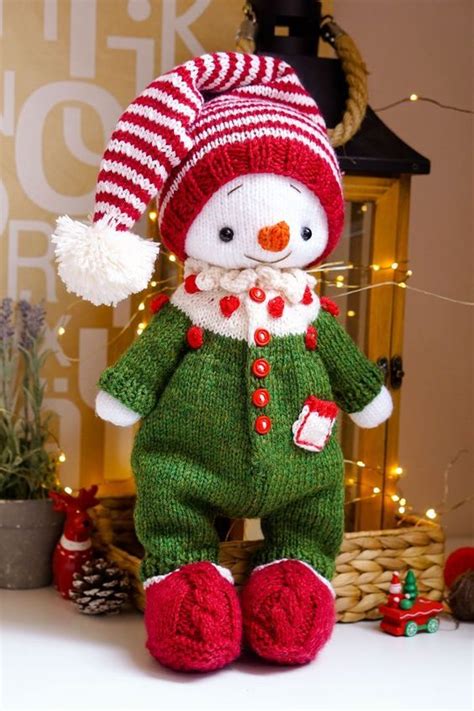 A Knitted Snowman Doll Sitting On Top Of A Table Next To Christmas