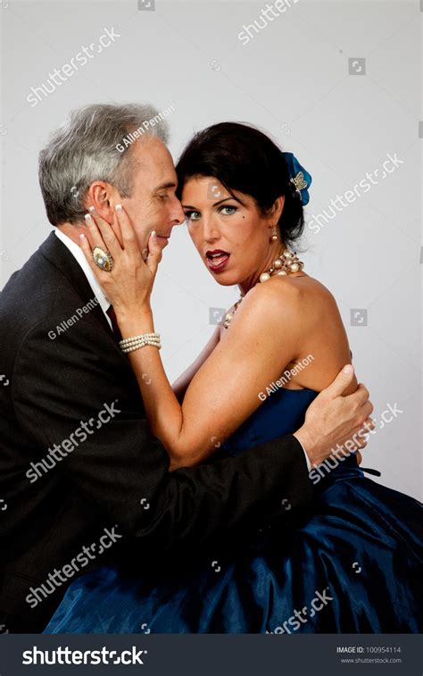 Lovely Mature Woman In A Dark Blue Evening Dress Showing Her Bare Shoulders And Looking At The