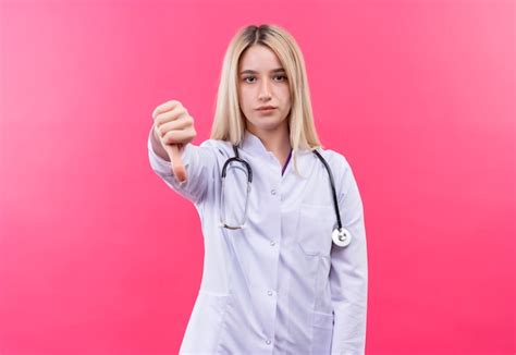 Médecin Jeune Fille Blonde Portant Un Stéthoscope En Blouse Médicale Son Pouce Vers Le Bas Sur