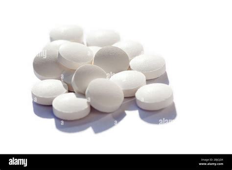 Many generic small round white pills, lots of little tablets on white background closeup. simple