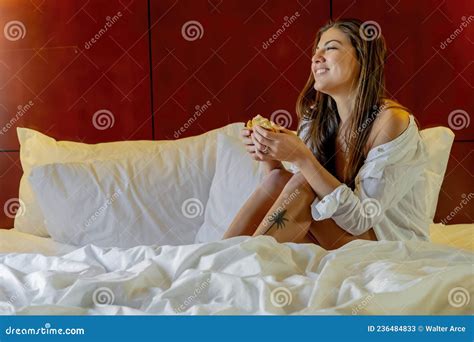 Gorgeous Hispanic Model Poses In Lingerie While Eating Breakfast In Bed In A Bedroom Environment