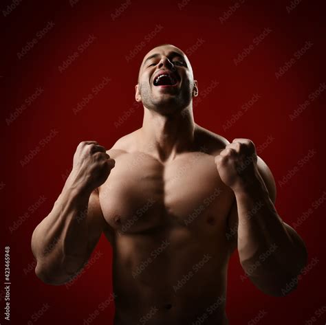 Strong Man Bodybuilder Stands With Naked Chest Shirtless Holding Up His Clenched Fists And