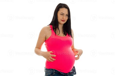 Cute Brunette Pregnant Woman In Bright Pink Shirt Touching Her Belly Isolated On White
